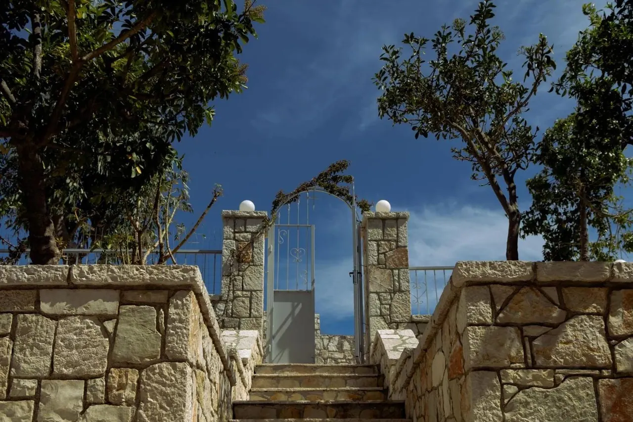 A wrought-iron gate between two stone pillars with the sea visible through it